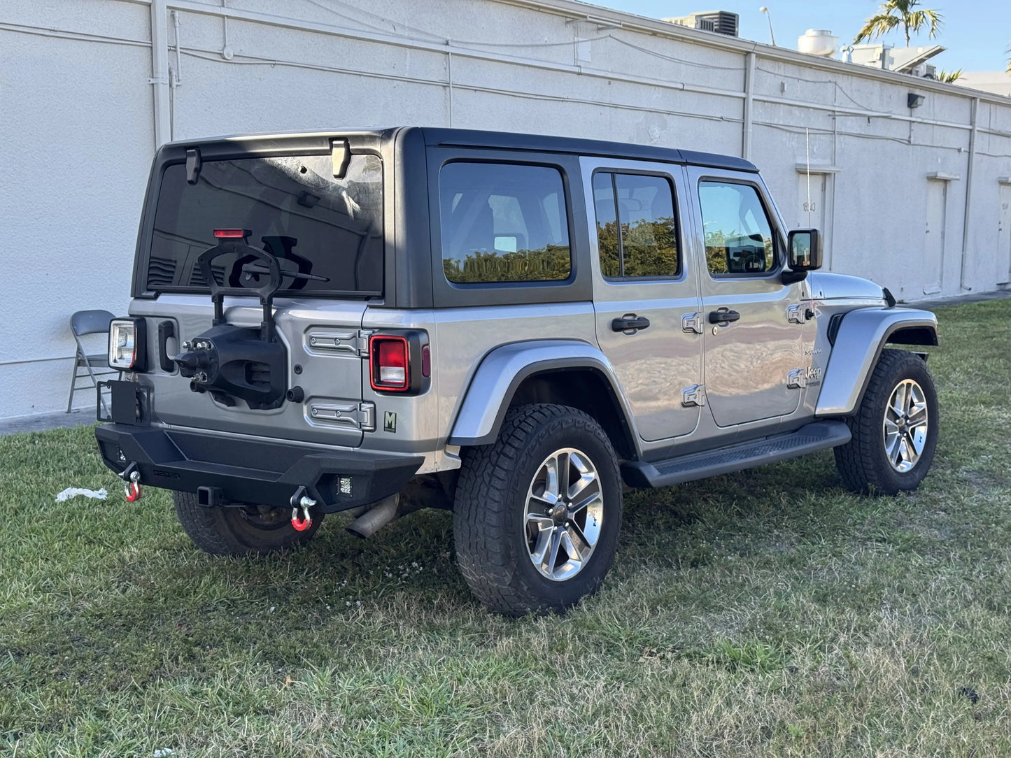 2020 Jeep Wrangler Sahara in silver with black accents, featuring a sturdy rear and off-road tires, listed as a repairable and salvage car for sale.