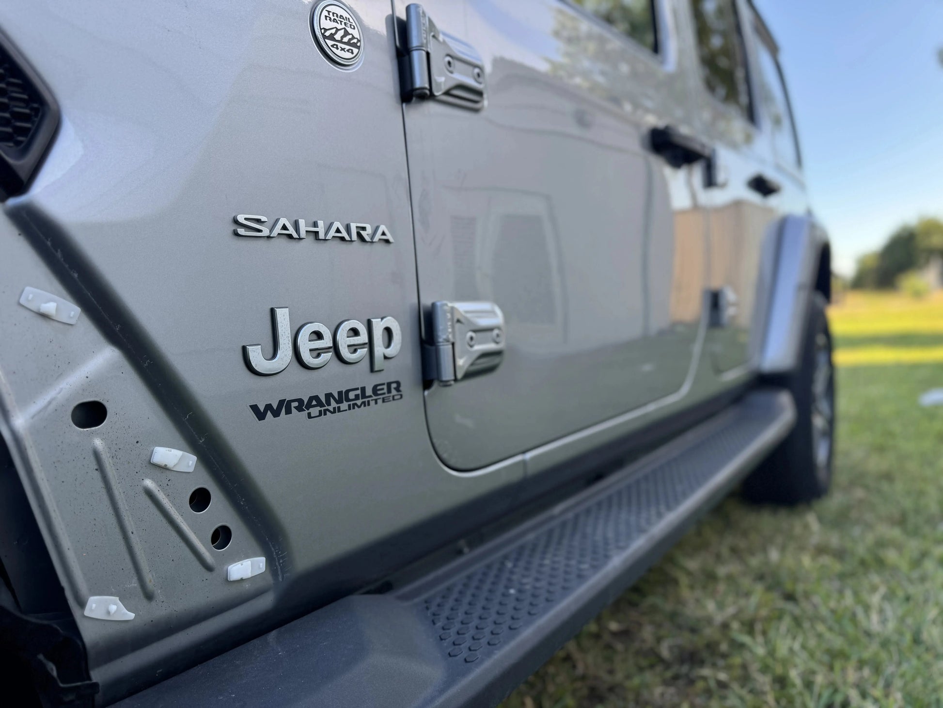 Side view of a 2020 Jeep Wrangler Sahara showcasing its logo and sleek design, available as a repairable & salvage car for sale.